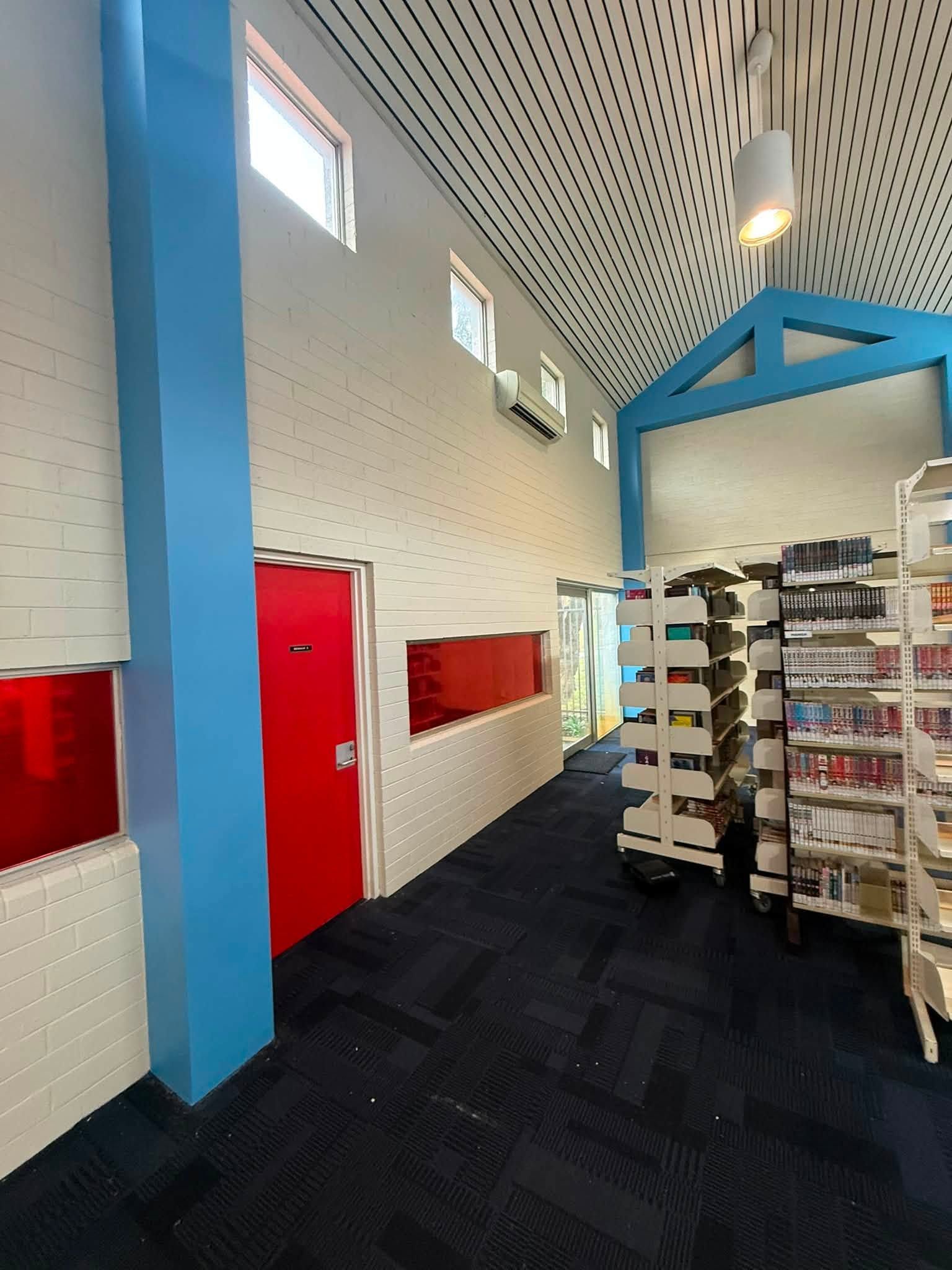 Bright store aisle with blue and white walls, red door, and shelves of merchandise under a patterned ceiling