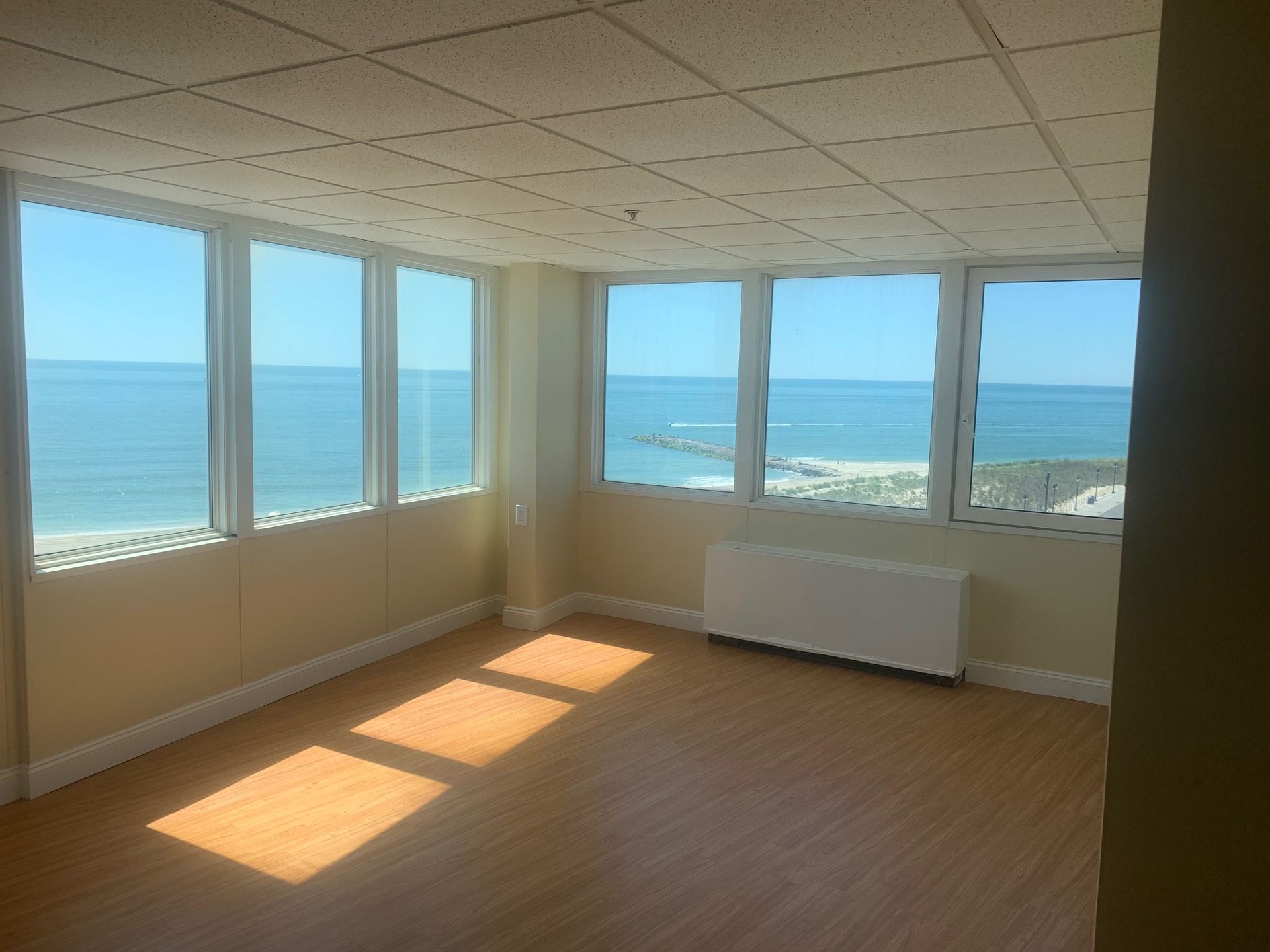 An empty room with lots of windows overlooking the ocean.