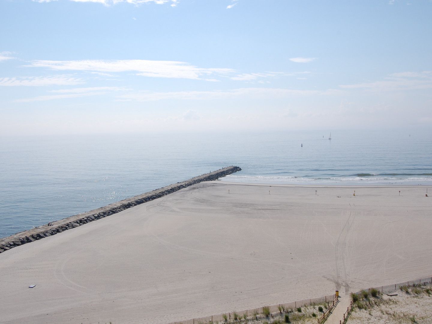 An aerial view of a beach with a pier in the distance.