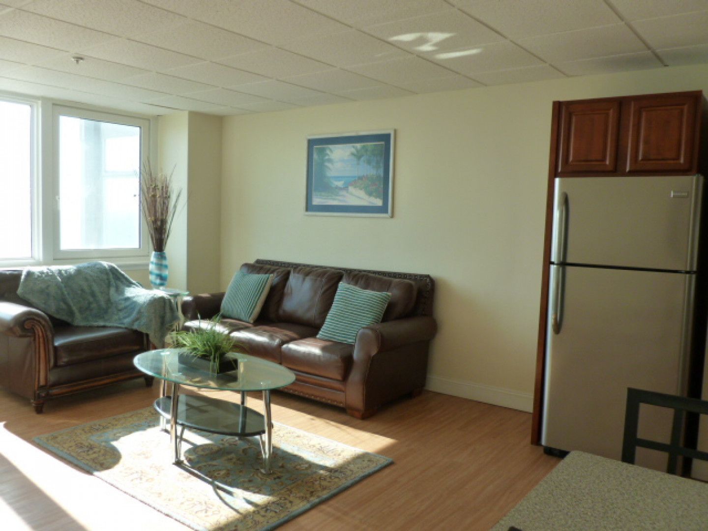 A living room with a couch a coffee table and a refrigerator