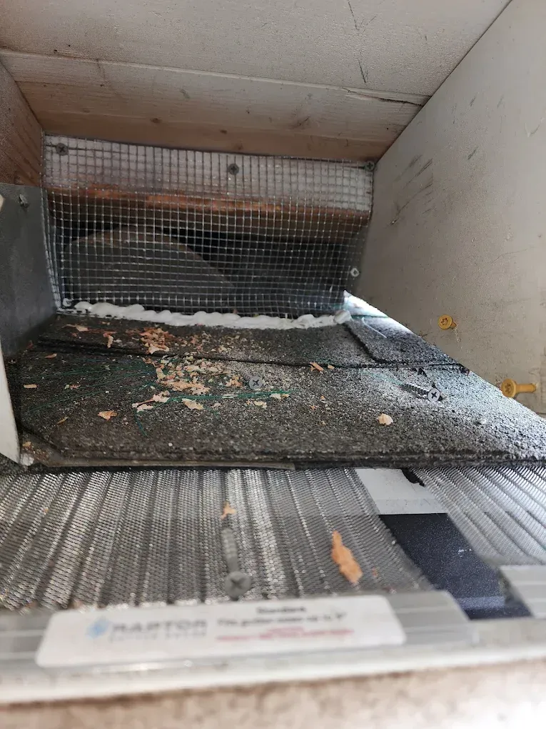 Dirty ventilation duct interior with metal mesh and debris on the floor.