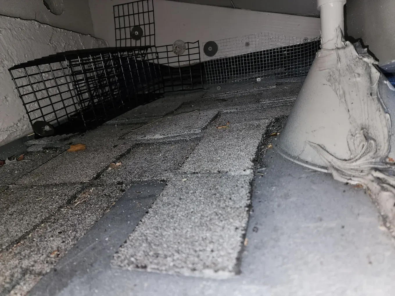 Gravel-filled rooftop channel with a white pipe and black mesh barrier along the sides