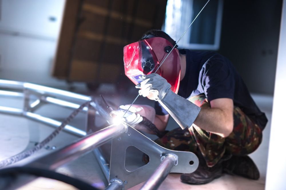Welder Wearing a Red Mask, Welding Metal Frame in a Workshop — GC Custom Fabrication in Robina, QLD