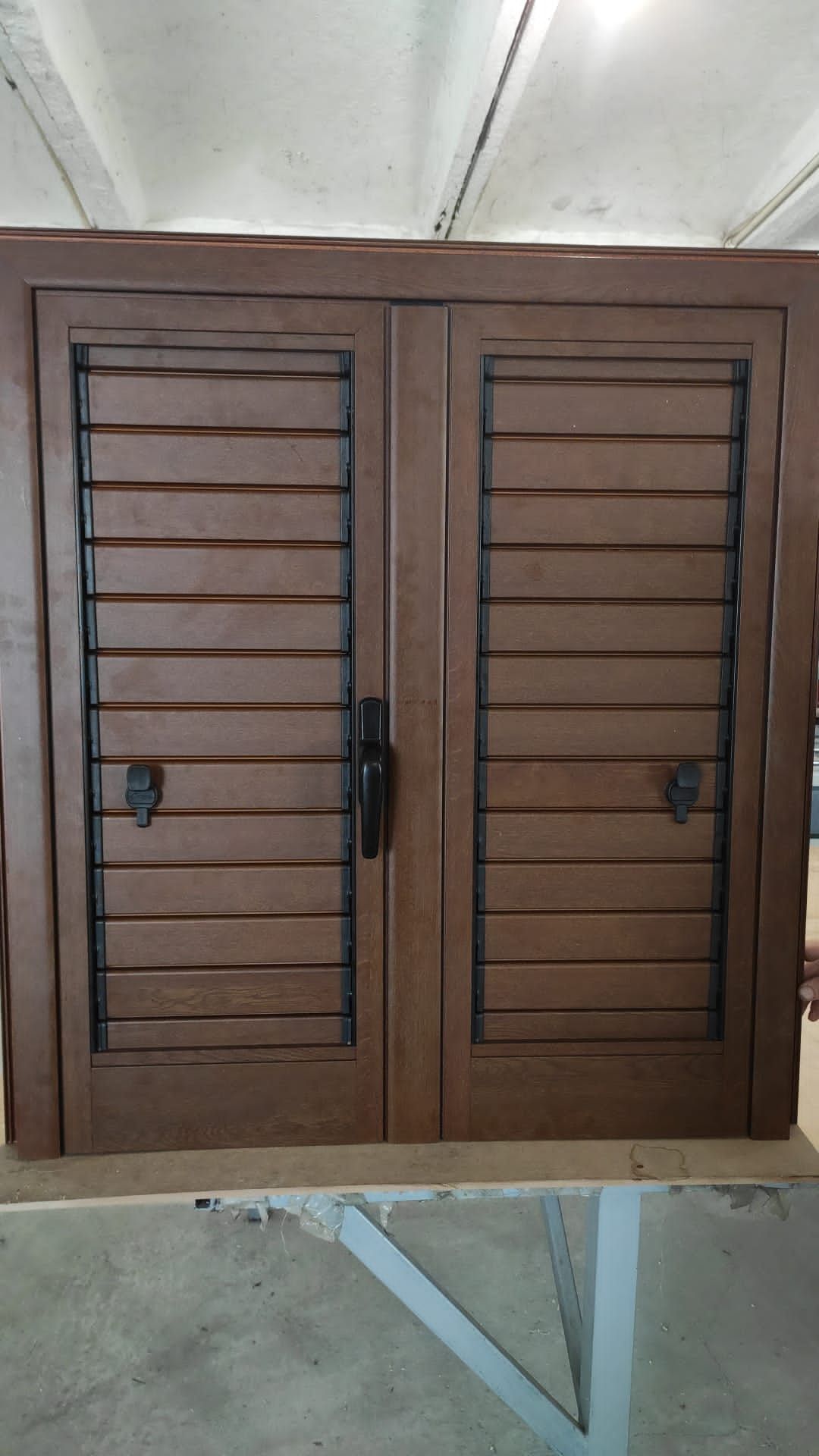 Porte doppie chiuse in legno marrone, a persiana, con maniglie nere e lucchetti.