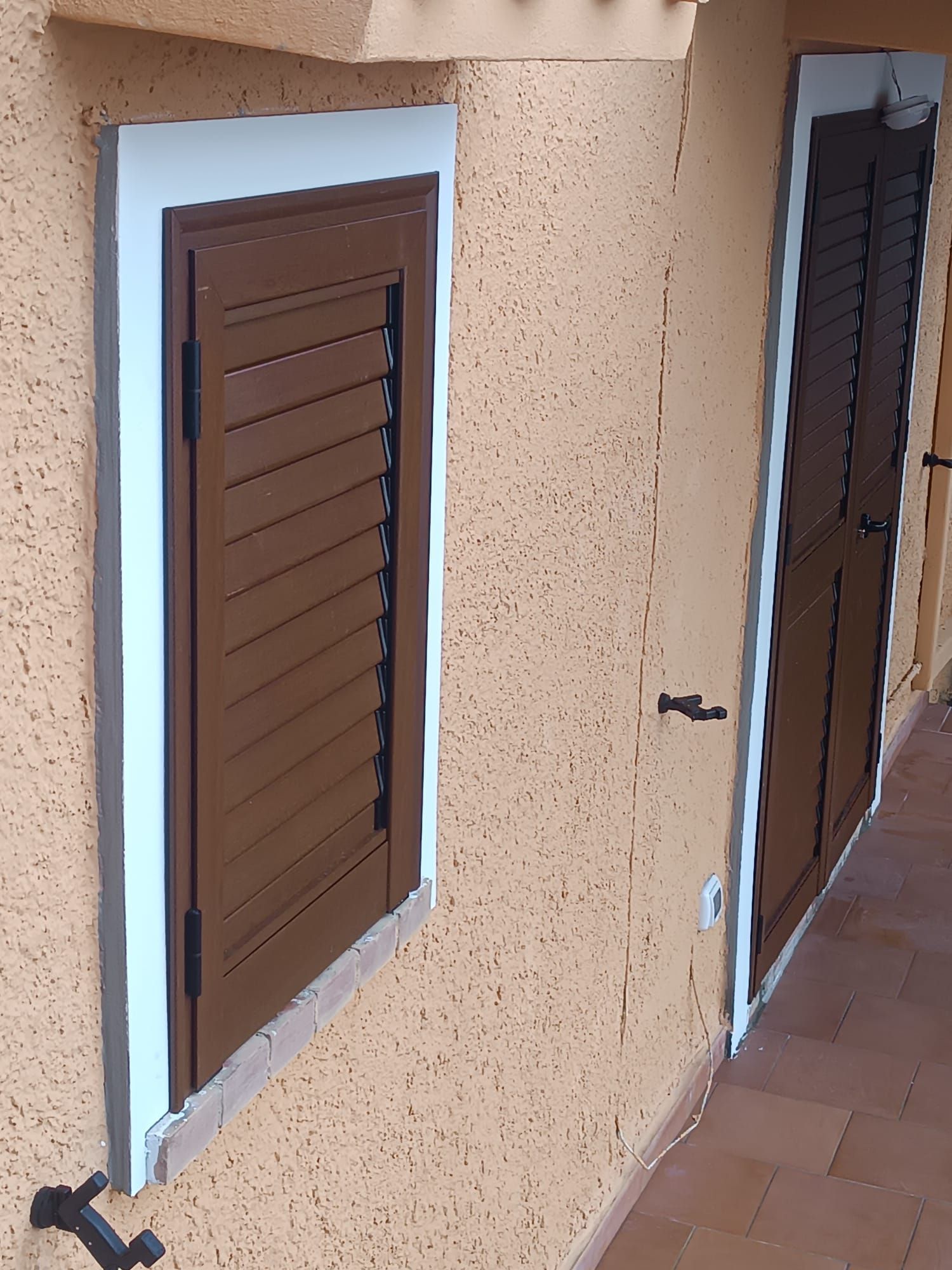 Persiane marroni in un corridoio in stucco beige con pavimento piastrellato