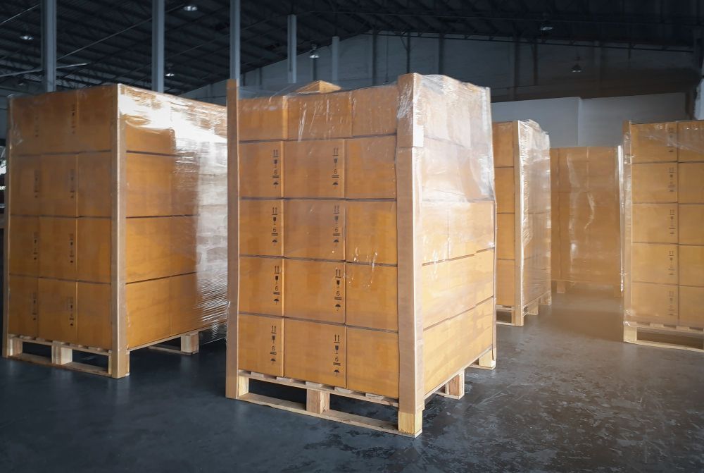 A warehouse filled with wooden pallets and boxes wrapped in plastic.