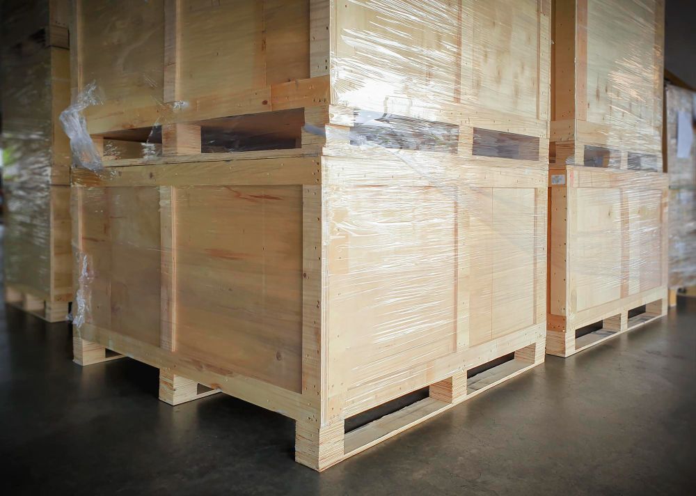 A row of wooden crates sitting on top of wooden pallets in a warehouse.