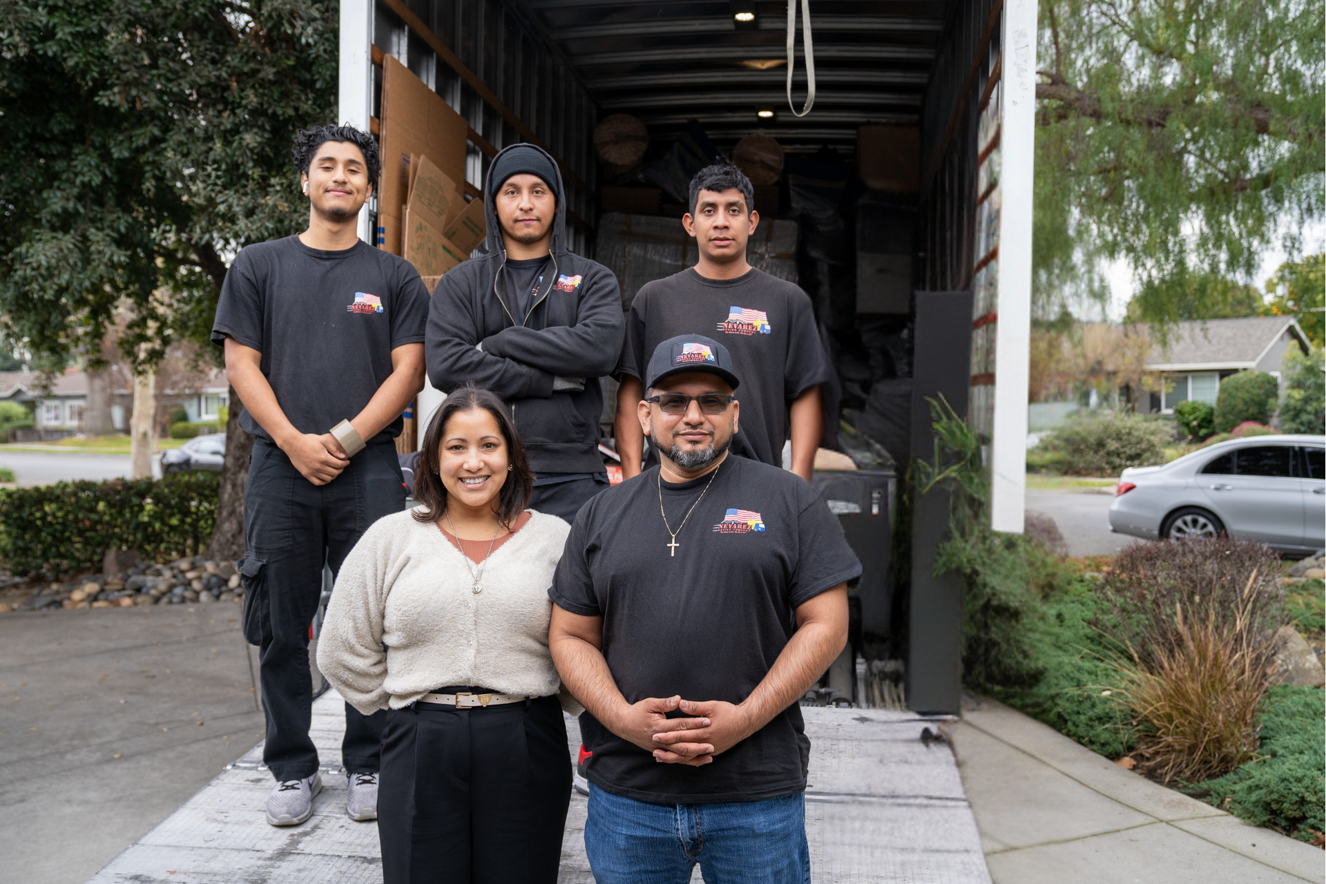 A group of movers are posing for a picture in front of a truck.