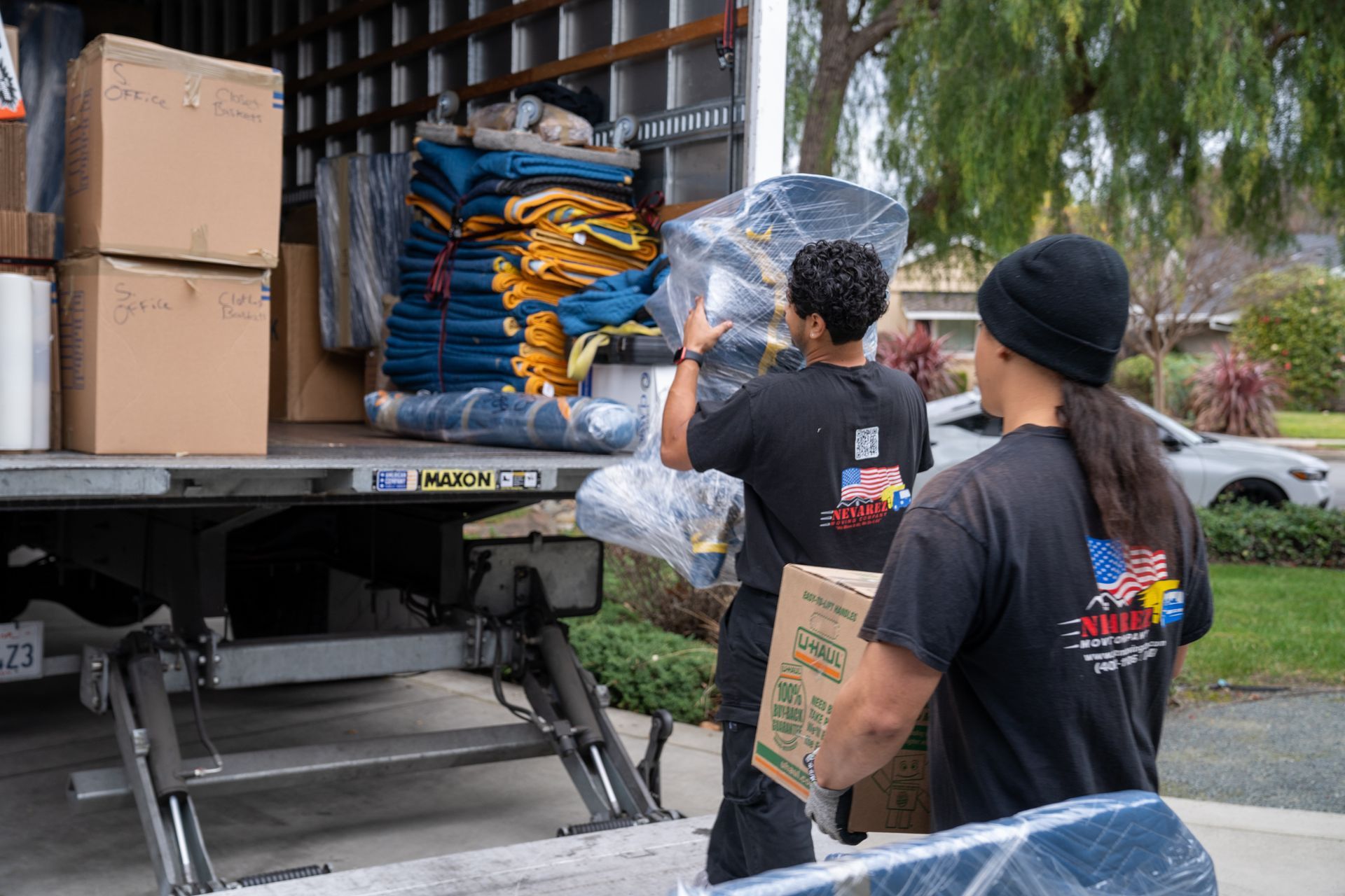 Two men are loading boxes into a moving truck.