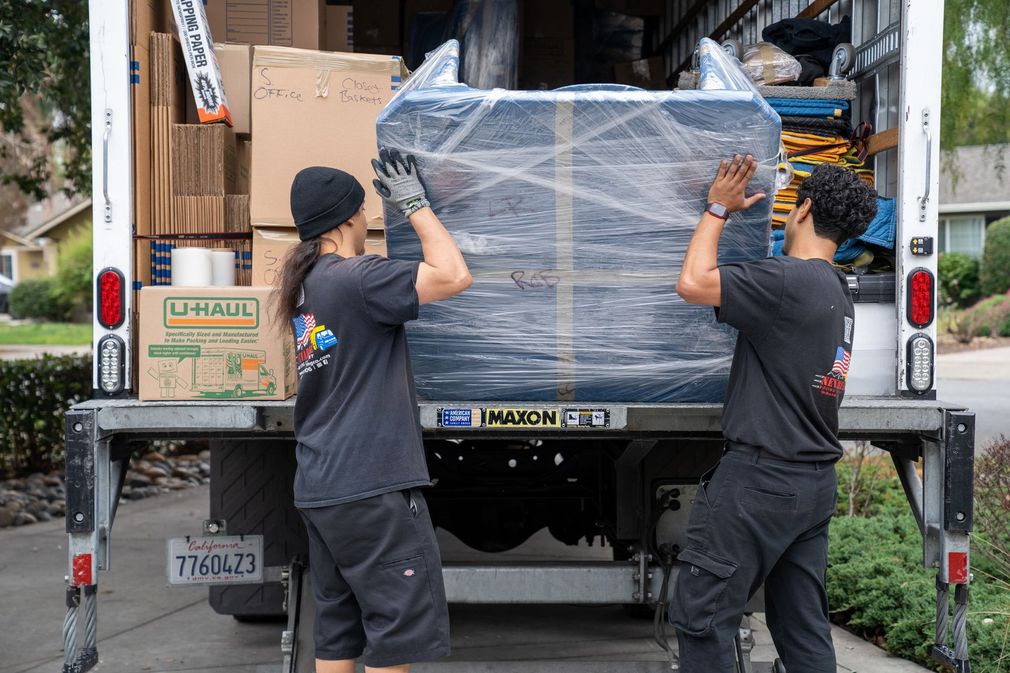 Two men are loading a large piece of furniture into a truck.