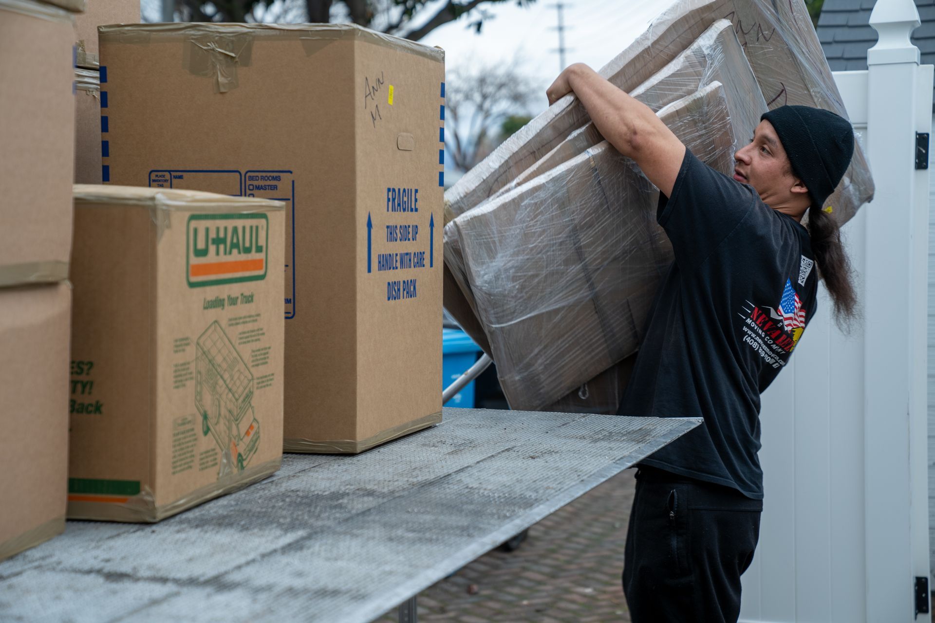 A man is carrying a stack of cardboard boxes on his shoulders.
