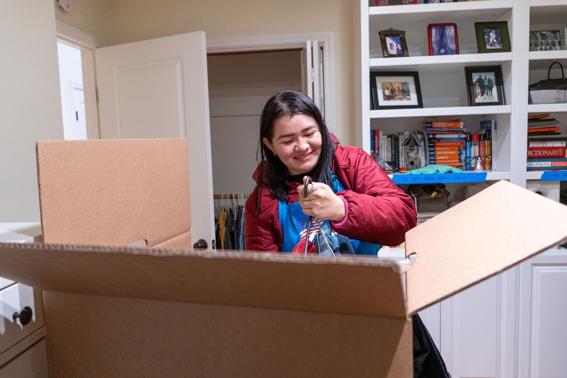 A woman is sitting in a cardboard box in a living room.
