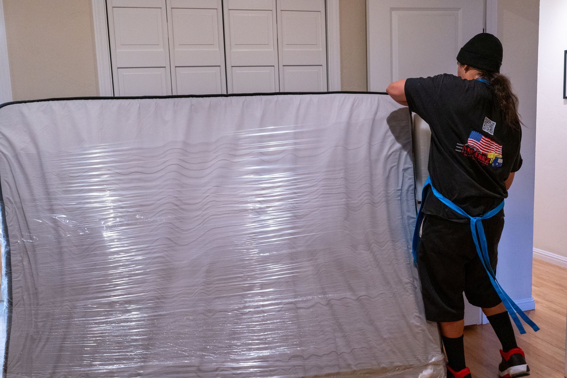 A man in a black shirt is standing in front of a large piece of plastic.