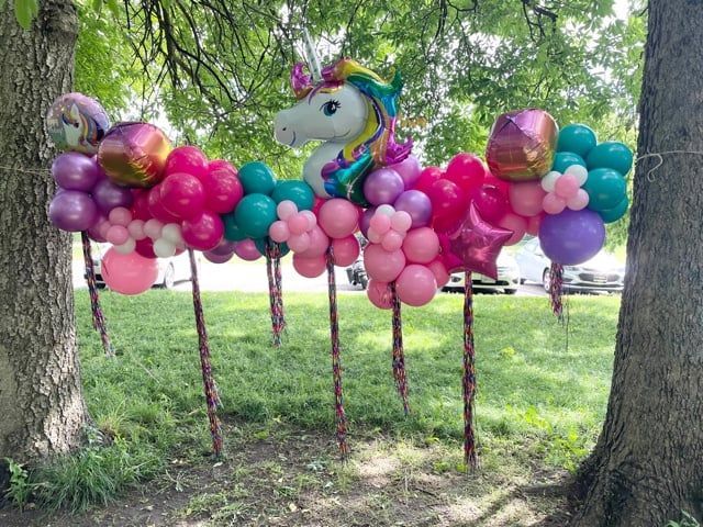 A unicorn balloon is sitting on top of a bunch of balloons.