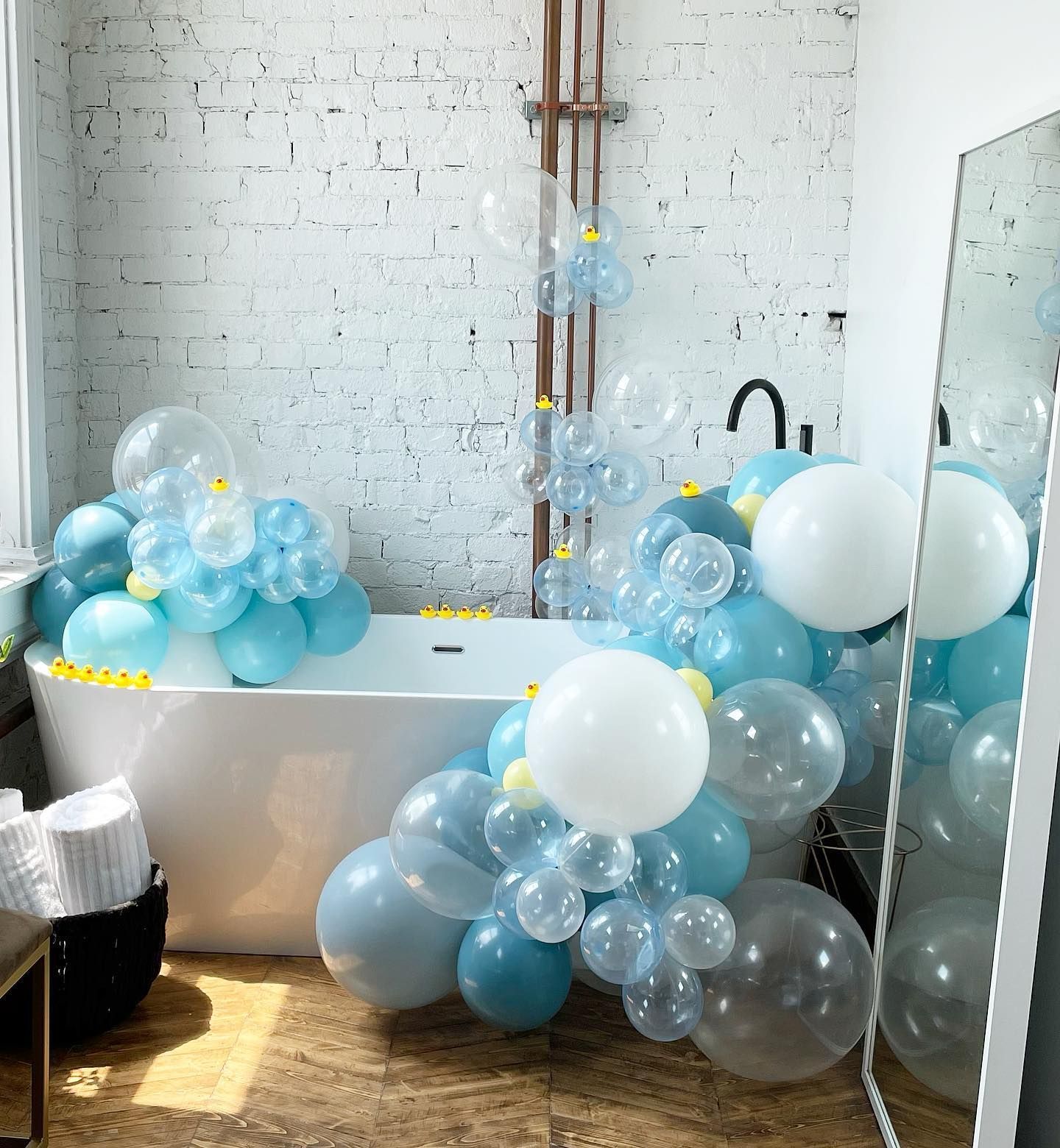 A bathtub filled with blue and white balloons in a bathroom.