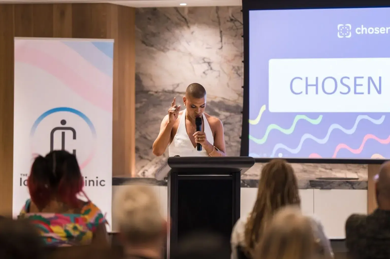Person speaking at a podium with a logo on the left and 