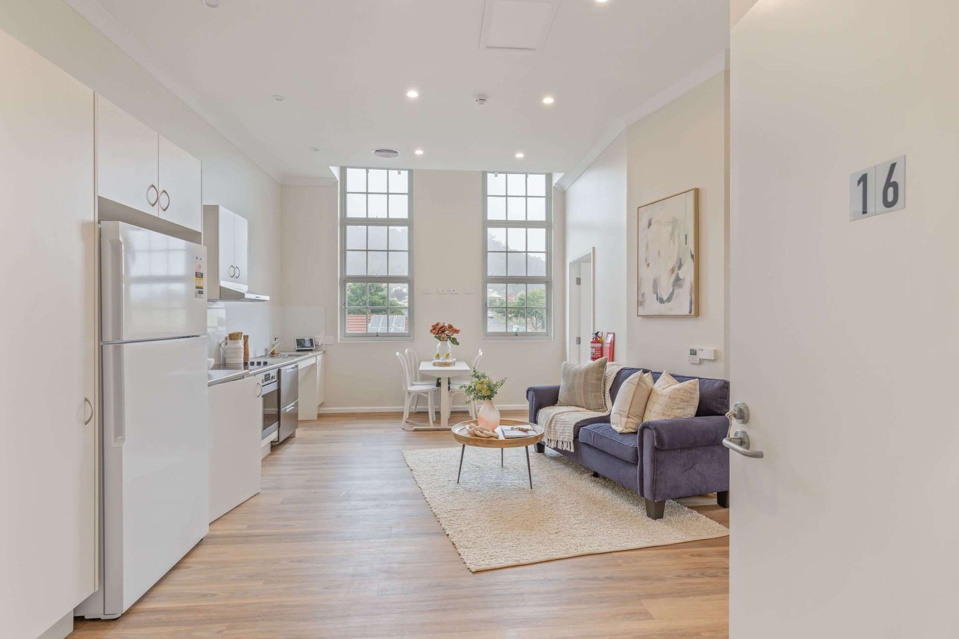 Bright apartment interior with kitchen, living area, and large windows.