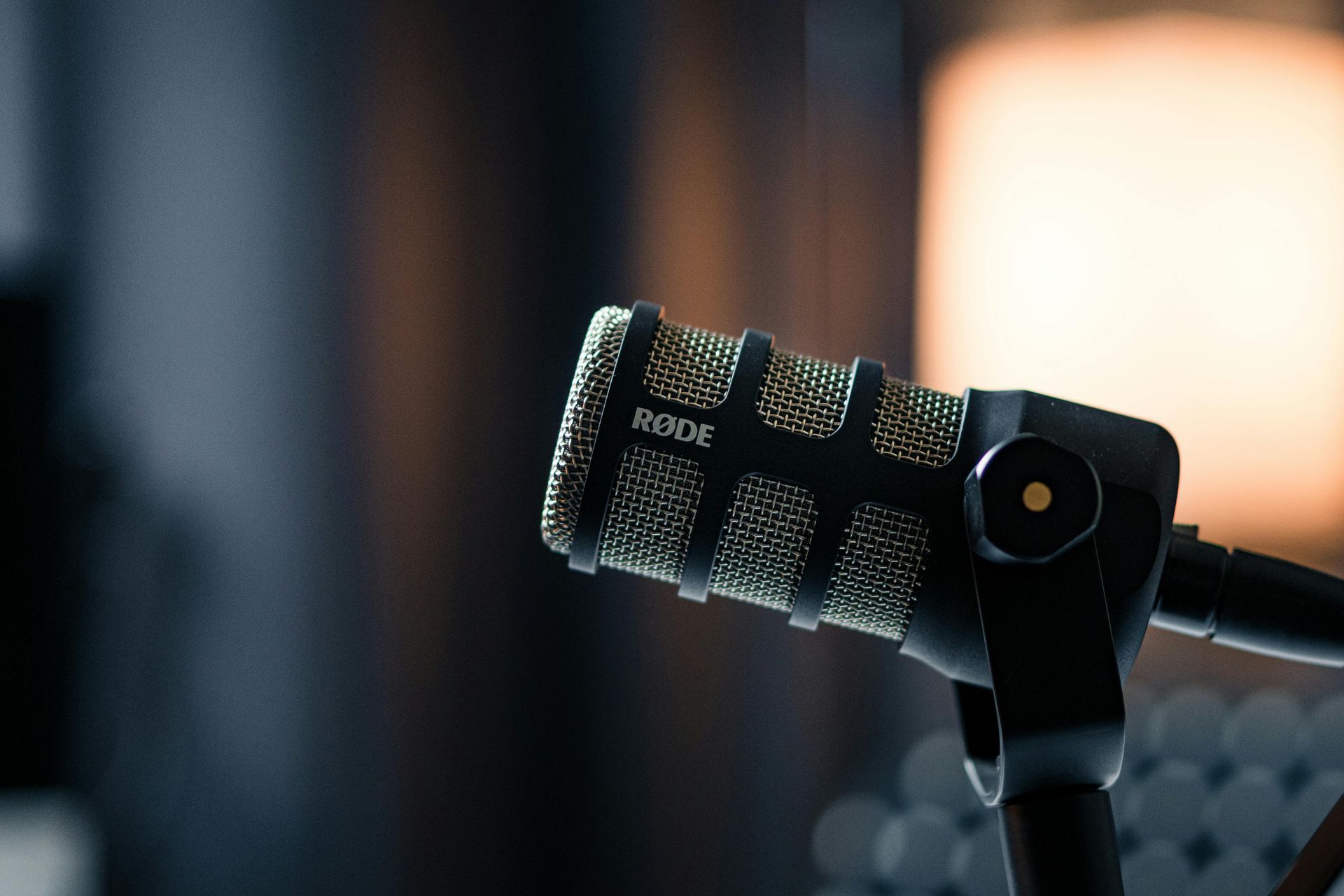 A gold and black microphone, close-up, in a dark studio.