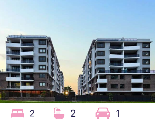Two modern apartment buildings with balconies, gray and white exterior against a dusk sky.