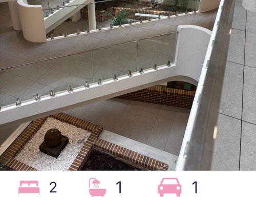 Multi-level interior with white walls, glass railings, and a small garden.