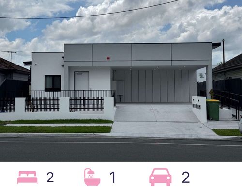 A modern white villa on Louis Street boasts a flat roof and clean lines, complemented by a covered driveway and sleek black railing. The partly cloudy sky frames this Granville gem, with a green bin by the entrance and neighboring houses on either side.