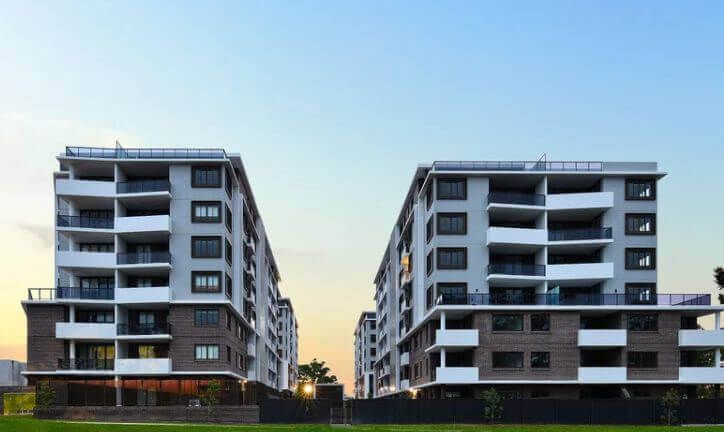 Two modern apartment buildings with balconies against a dusky sky.