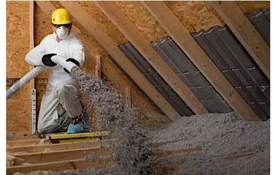 A man is blowing insulation into the attic of a house.
