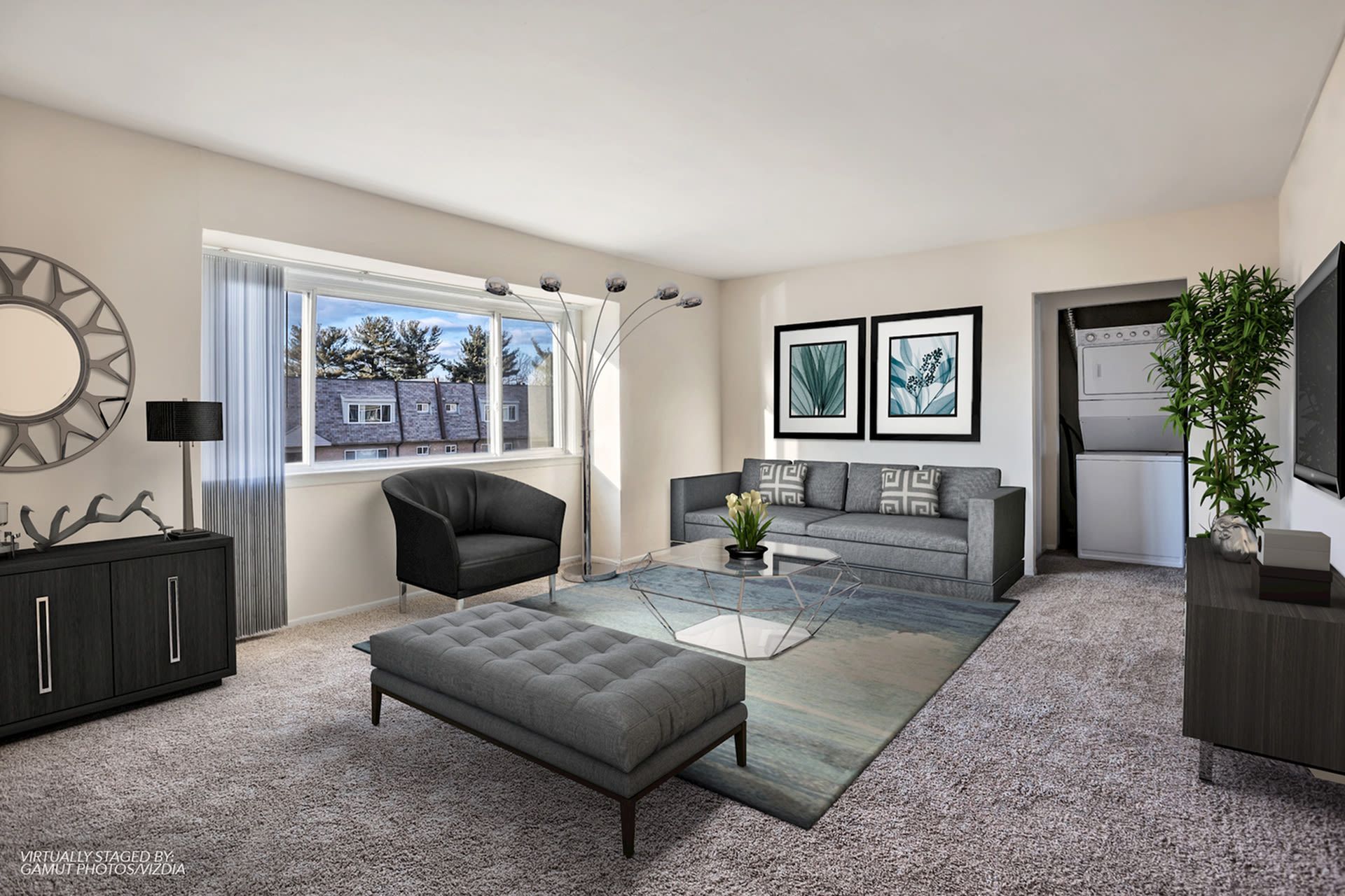 Furnished living room in a modern apartment with grey sofa, chairs, glass coffee table, and a laundry closet.