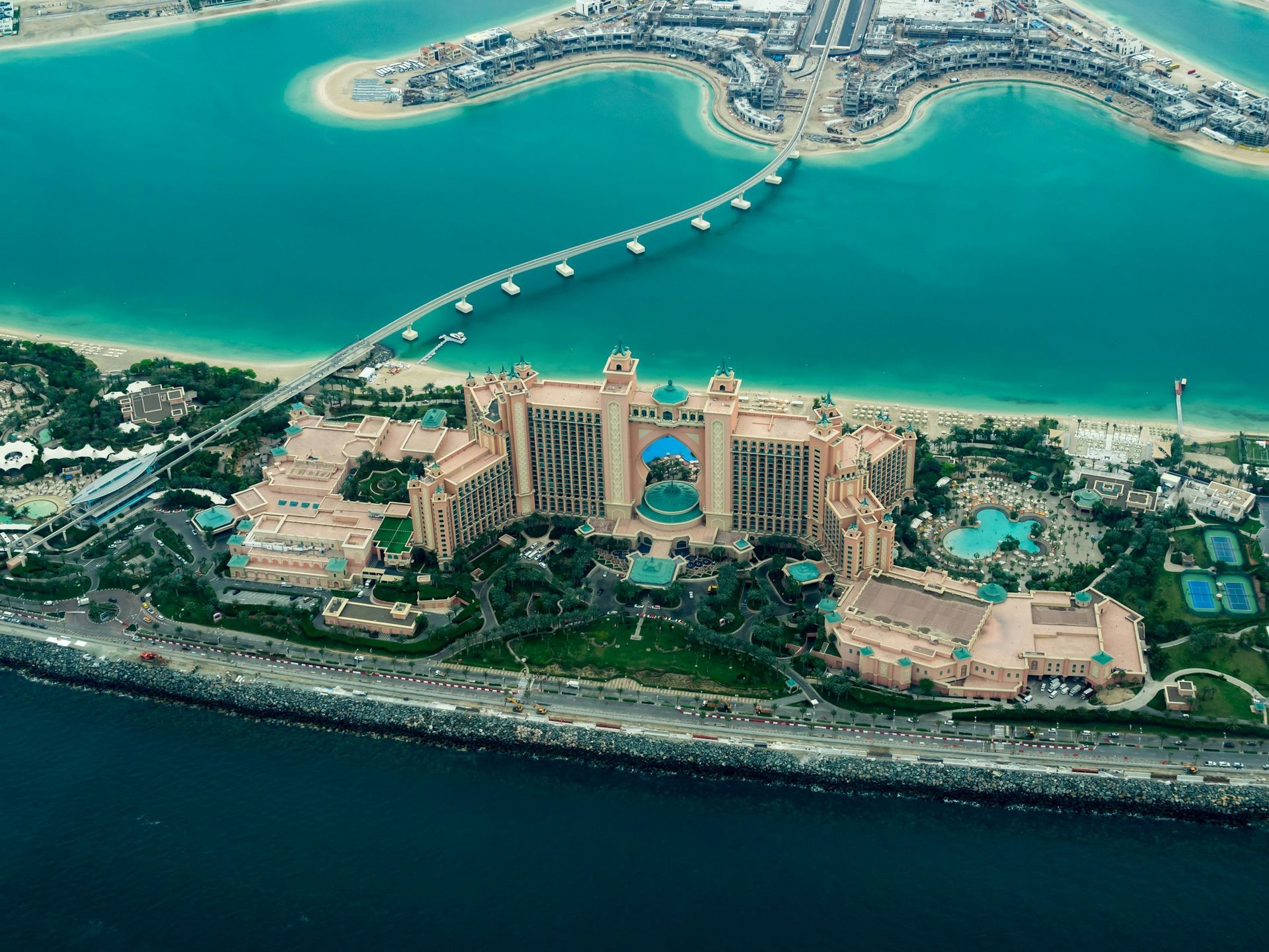 Aerial view of Atlantis, The Palm resort on a crescent-shaped island in Dubai, surrounded by turquoise water.