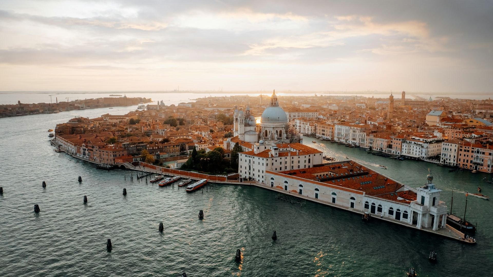 Aerial view of the Basilica di Santa Maria della Salute at the tip of a Venetian canal at sunset.