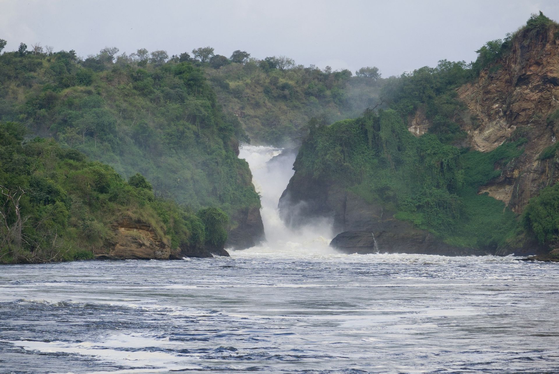 Murchison Falls, where the Nile River forces its way through a narrow, rocky gorge amidst lush green vegetation.