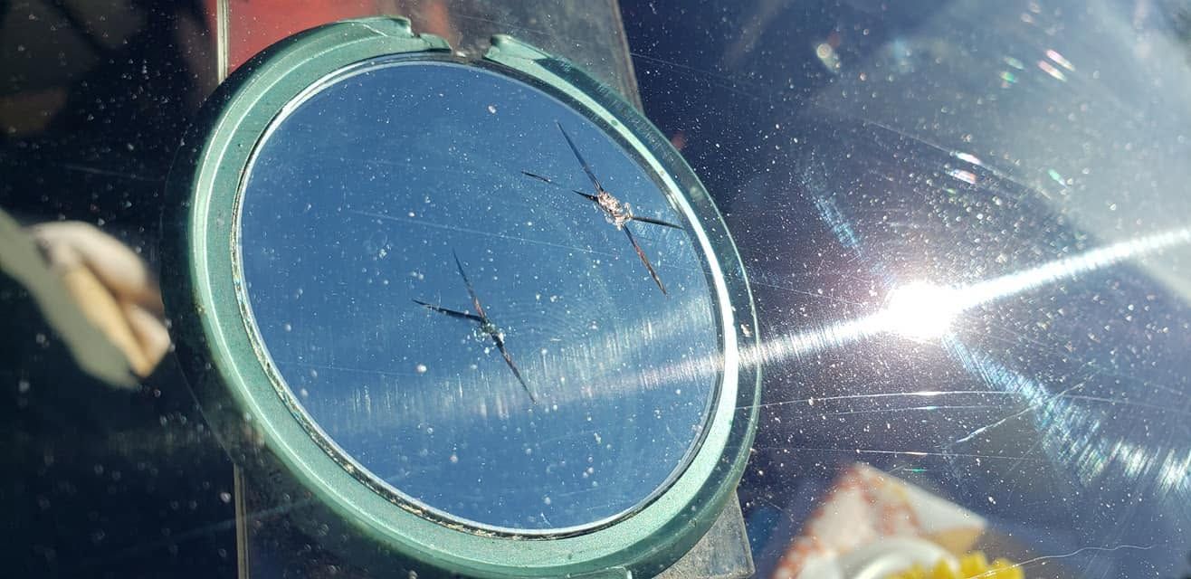 Close-up of a blue speedometer with sunlight glare on a car dashboard