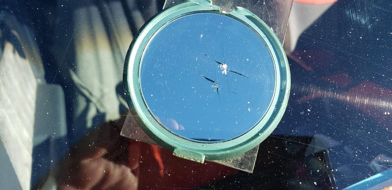 Close-up of a blue circular lid or cap with a green rim, showing small scratches and reflections.