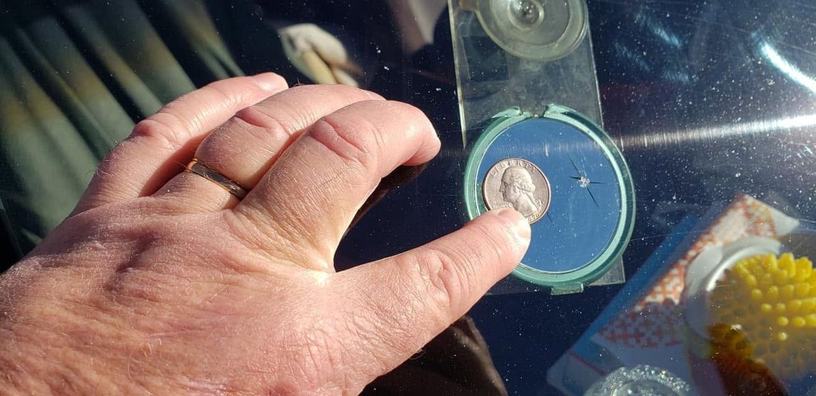 Hand holding a blue-taped compact disc on a reflective surface, with a small object centered on it.