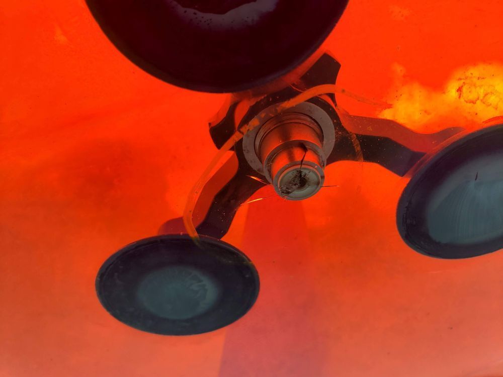 Close-up of a ceiling fan with dark blades against a bright orange-red background.