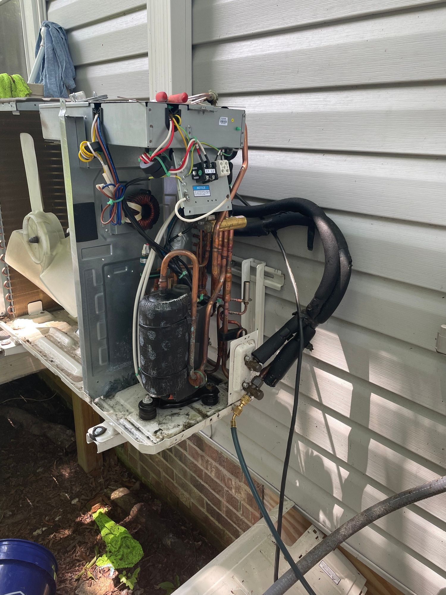 An air conditioner is being repaired on the side of a house.