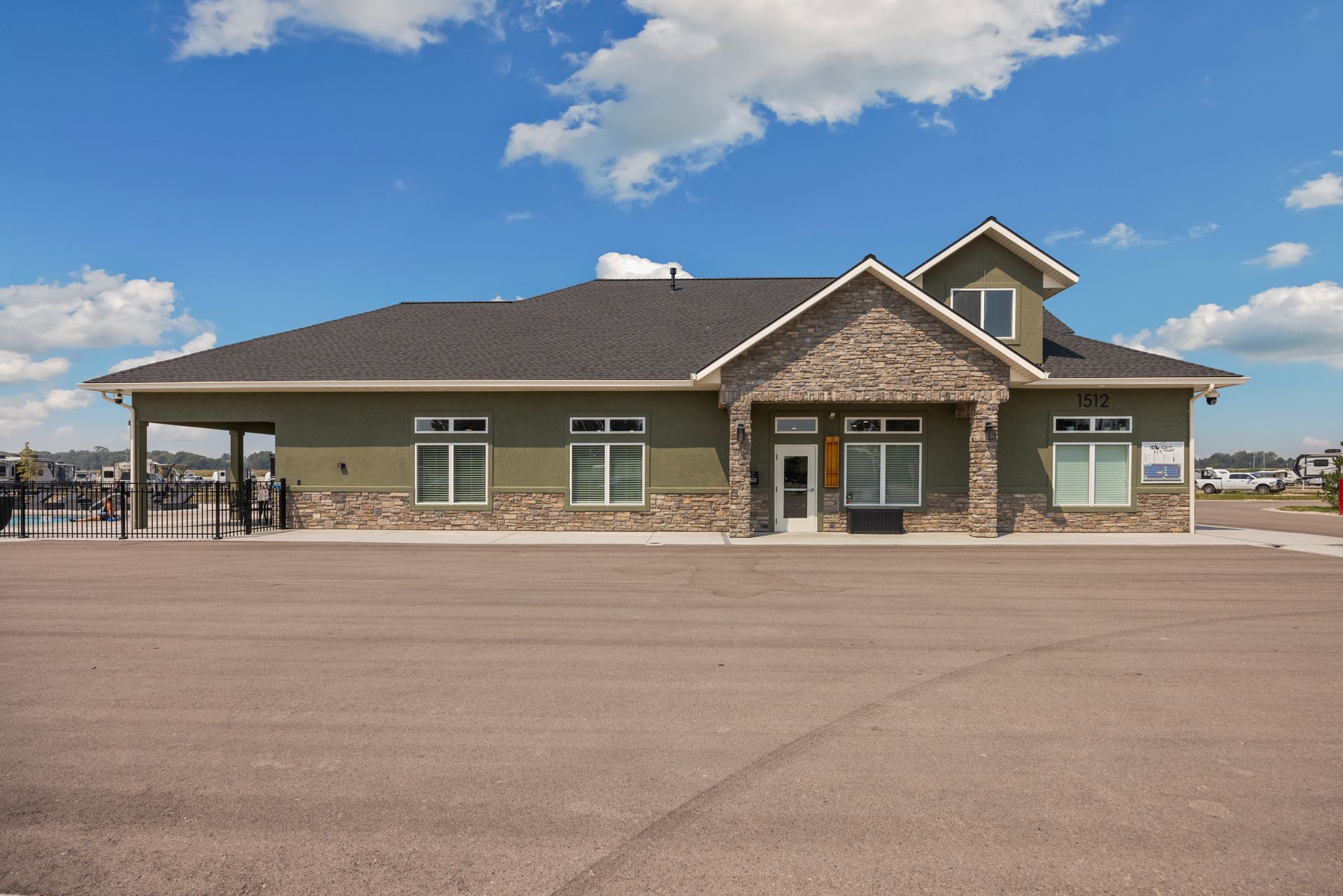 The single-story club house at IdaHome RV Resort with a covered entrance under a blue sky.
