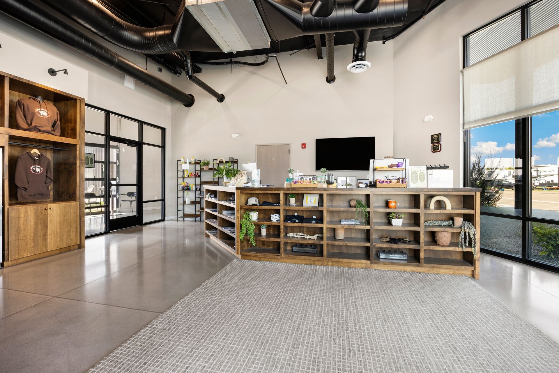 The main office at Sun Creek Point RV Resort with wooden display shelves, clothing rack, and large windows.