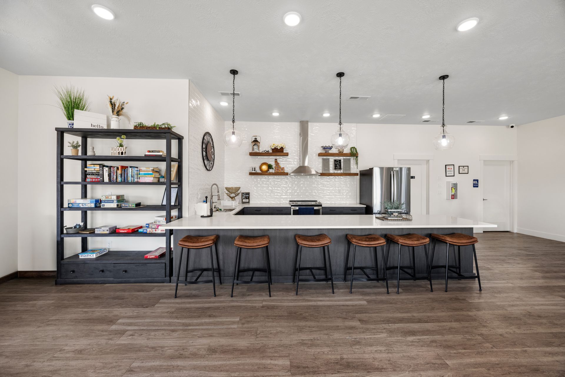 A modern open kitchen with island seating, and pendant lights in a bright living space at the Idahome RV Resort clubhouse.
