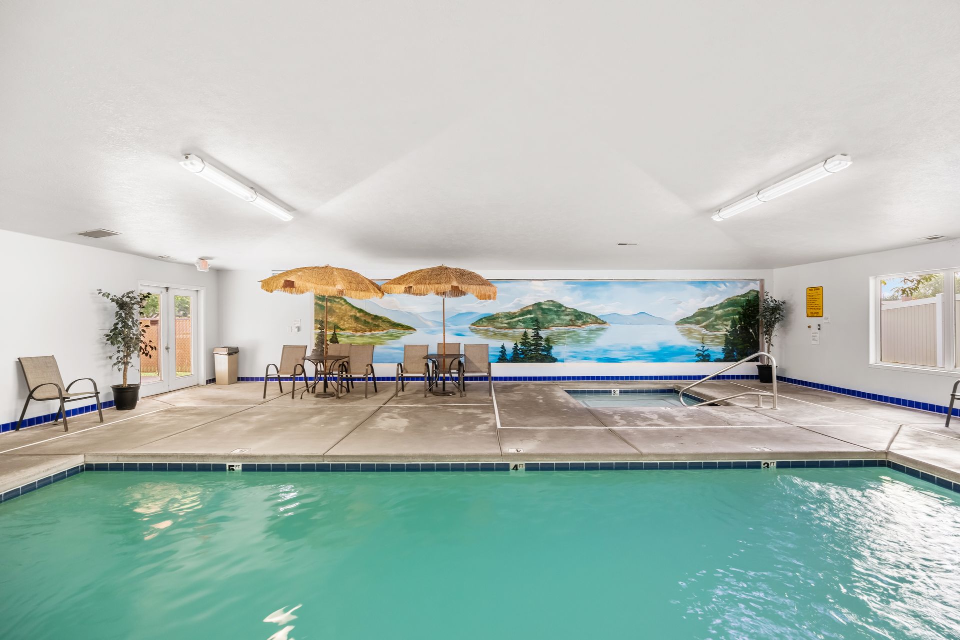 The Boise Meridian KOA indoor swimming pool with turquoise water, white walls, and a tropical mural in the background.