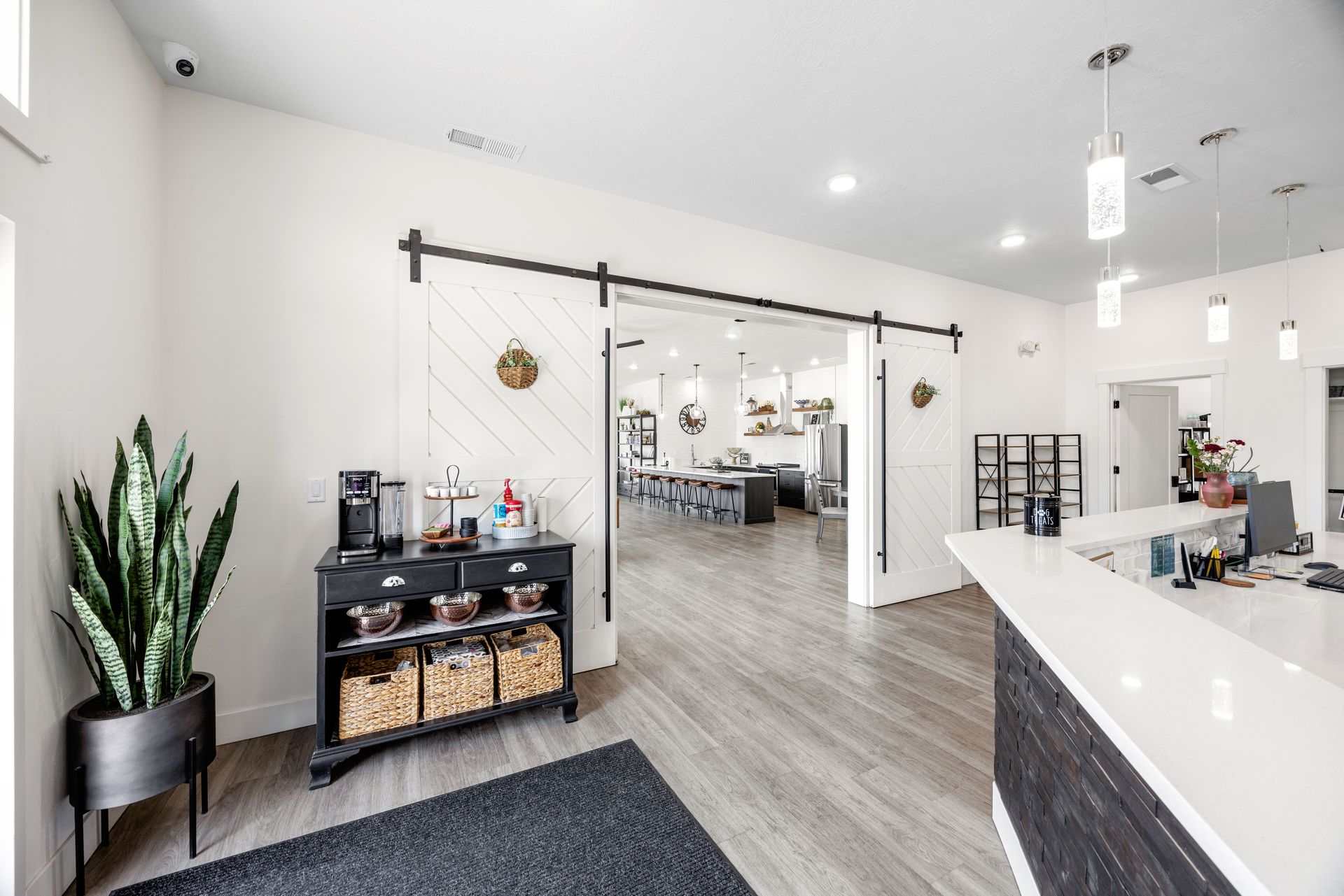 The bright modern office lobby, at Idahome RV Resort, with white walls, reception desk, plants, and a sliding barn-style doorway.