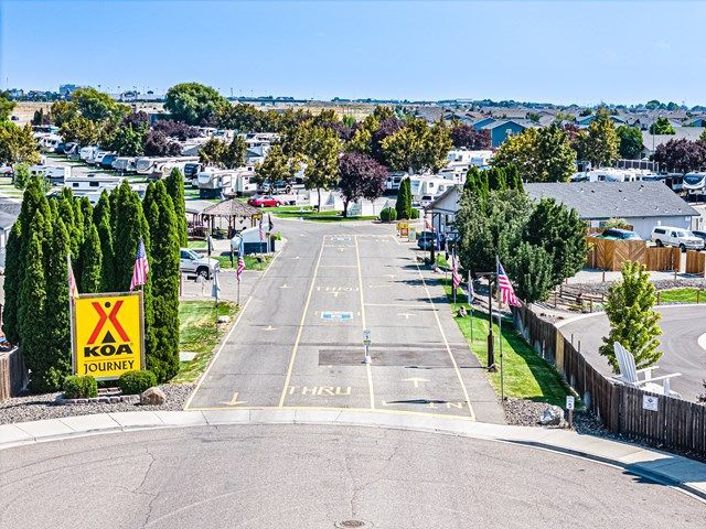 Wide view of the entrance of the Pasco Tri-Cities KOA with trees on both sides.
