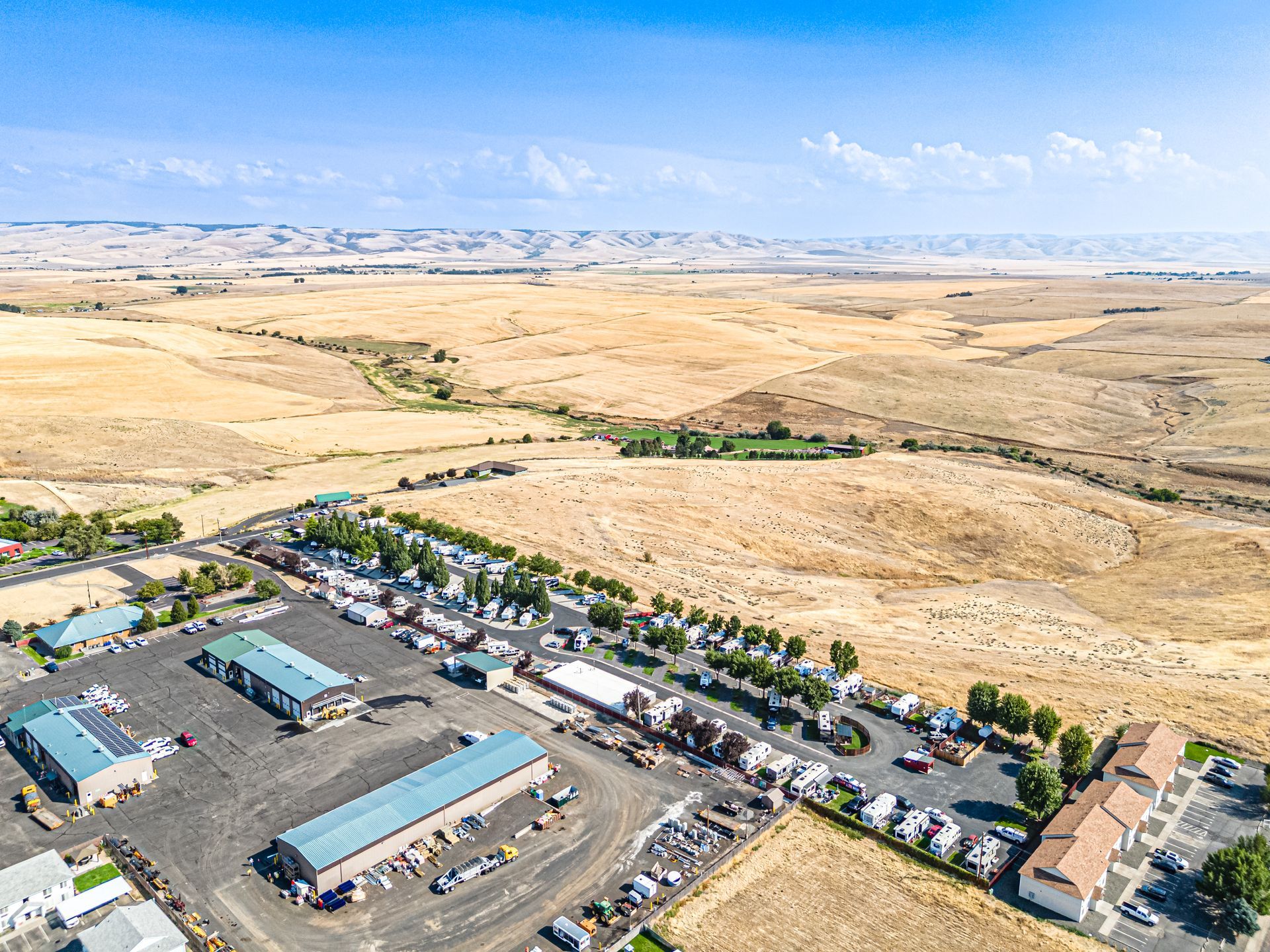 Aerial view of the Pendleton KOA beside a road, surrounded by vast sandy desert and low hills.
