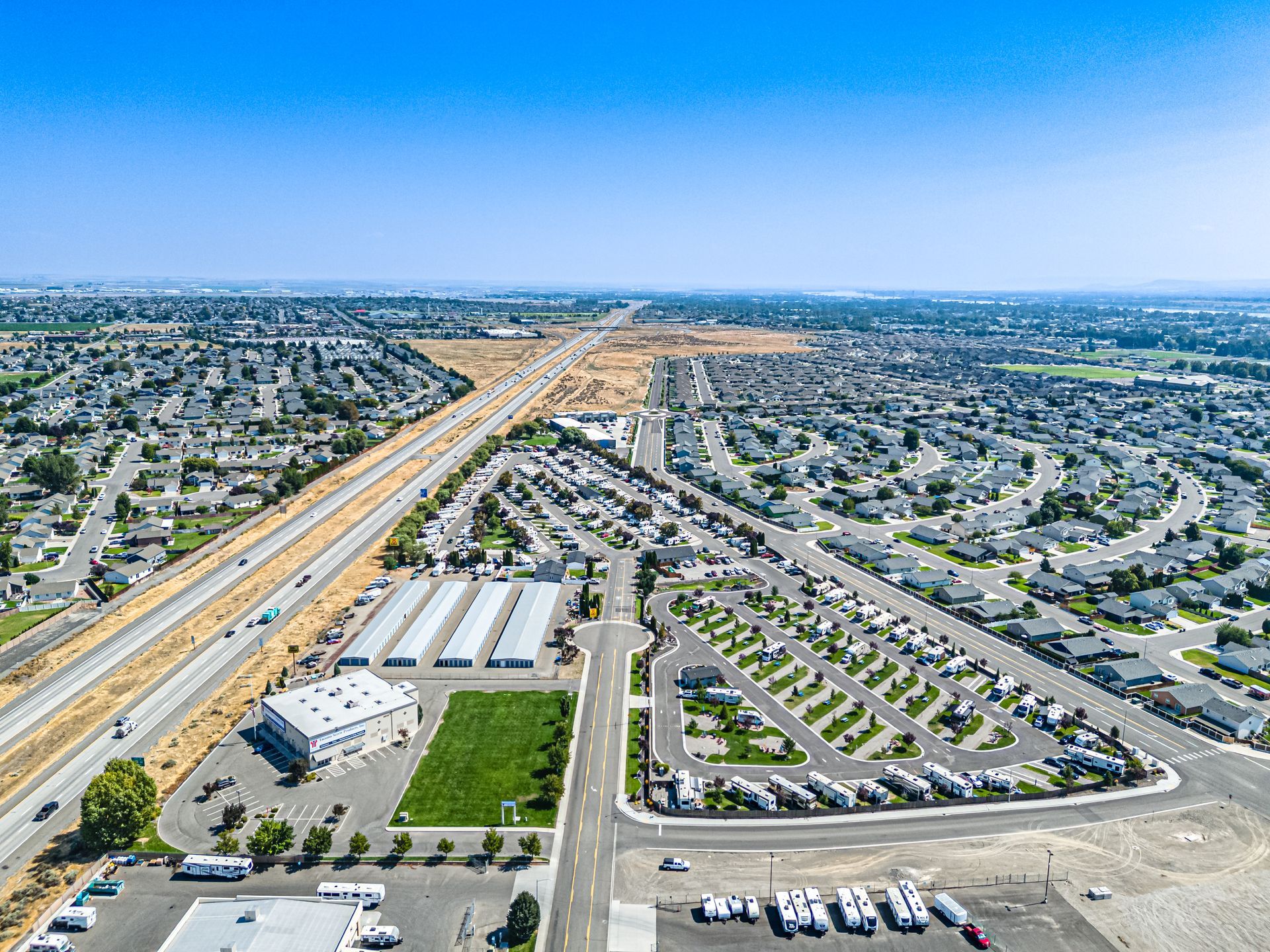 Aerial view of the Pasco Tri-Cities KOA with highways, RV pads, and scattered buildings under a clear blue sky.