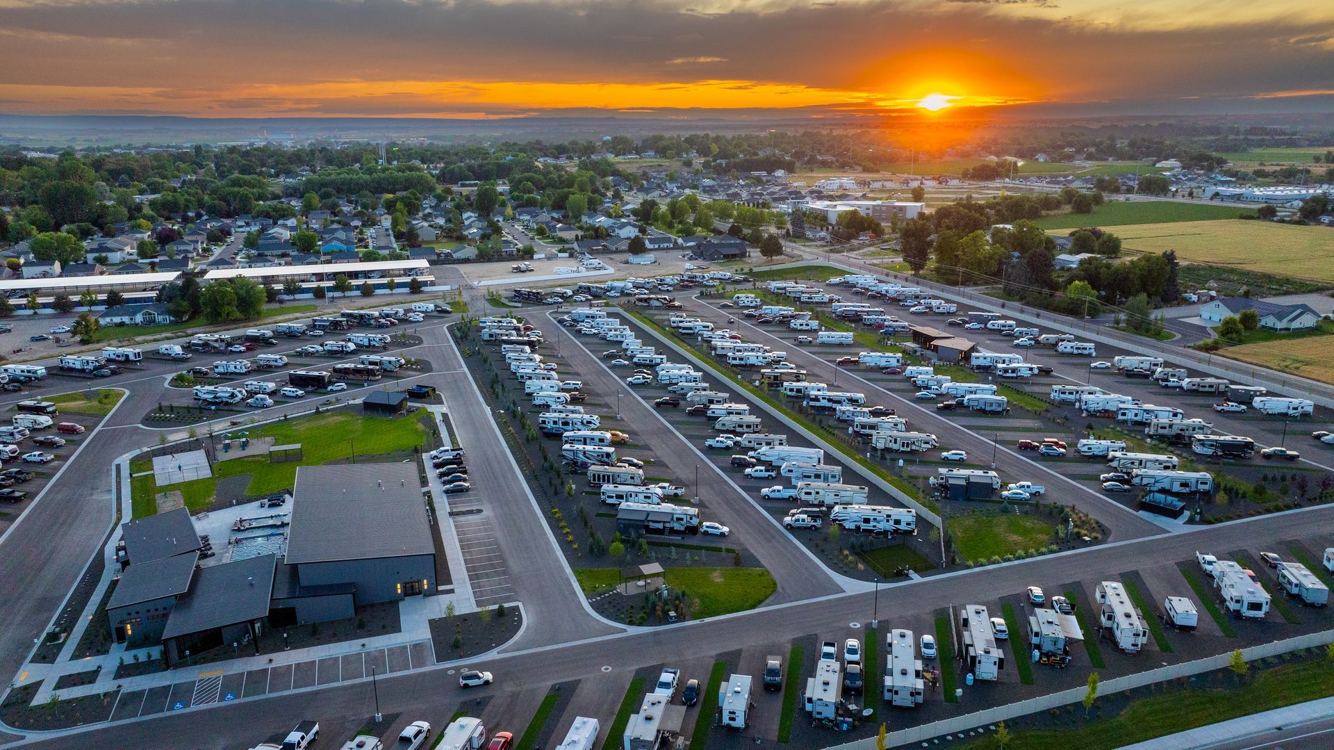 Aerial view of Sun Creek Point RV Resort at sunset, with rows of parked RVs under an orange sky.