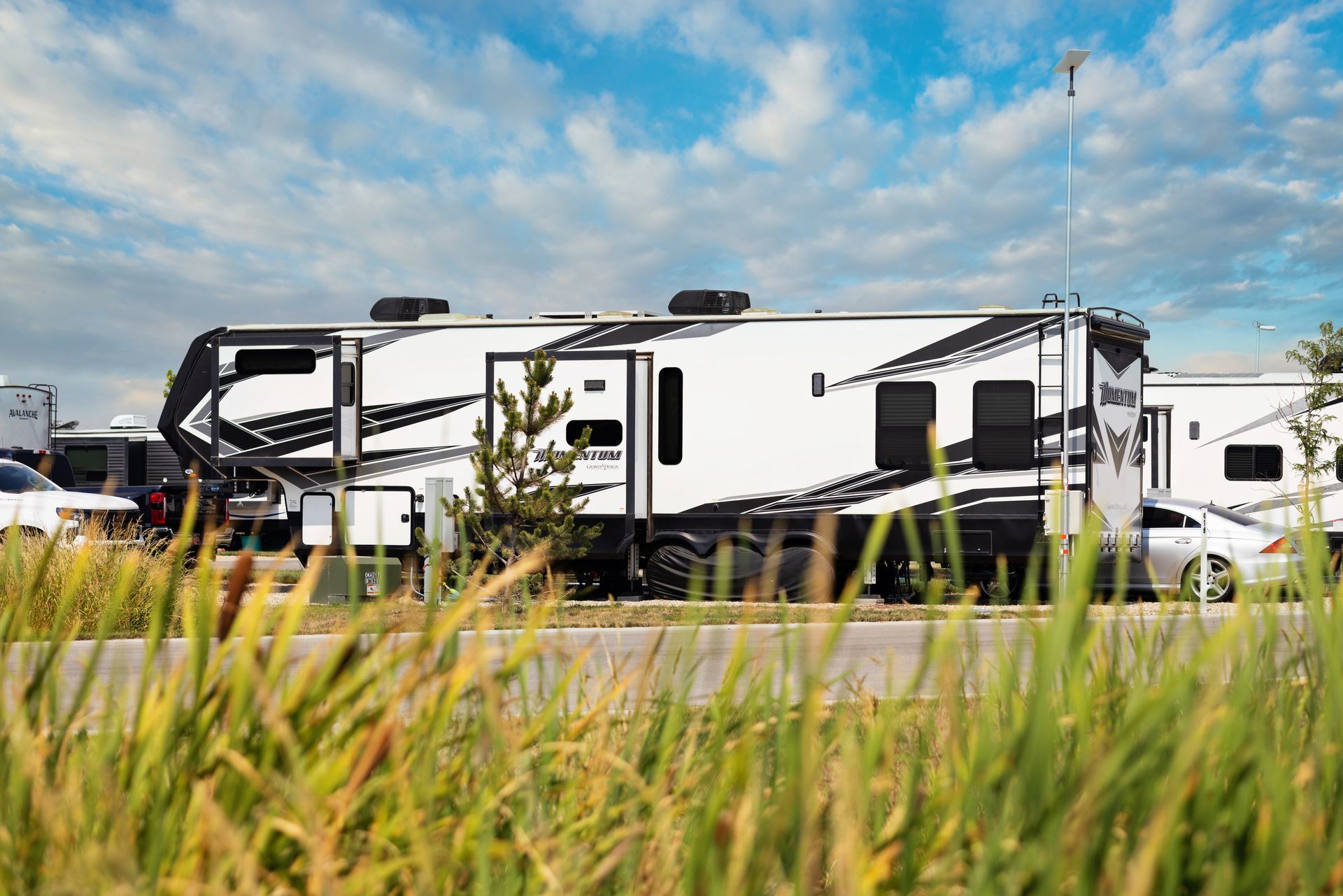White RV trailers parked at Idahome RV Resort under a clear blue sky.