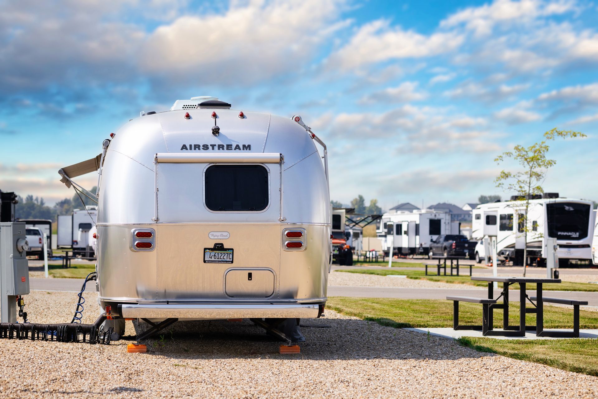 A silver Airstream trailer parked at Idahome RV Resort under a blue sky.