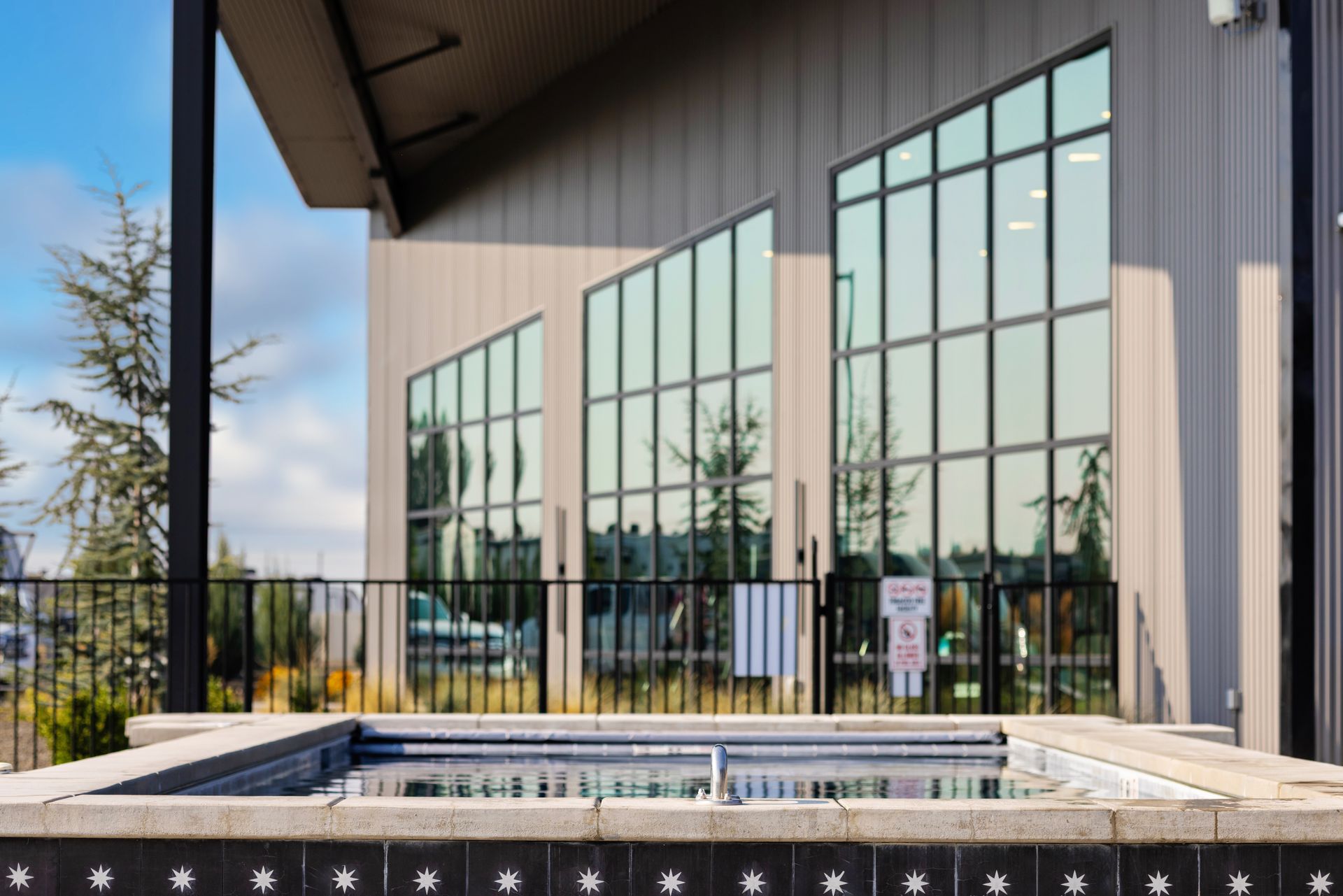 The hot tub and club house at Sun Creek Point RV Resort with tall windows, black railing.