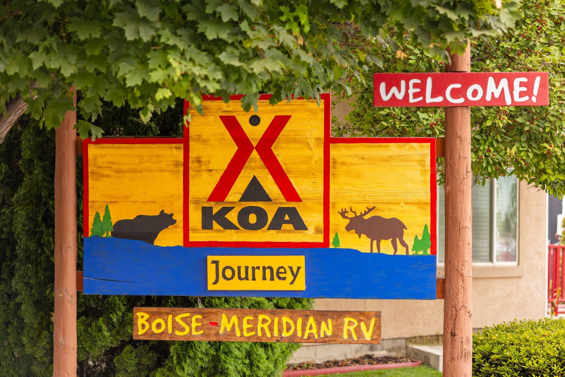 Colorful KOA Journey sign with “Welcome!” and “Boise Meridian RV” under leafy trees.