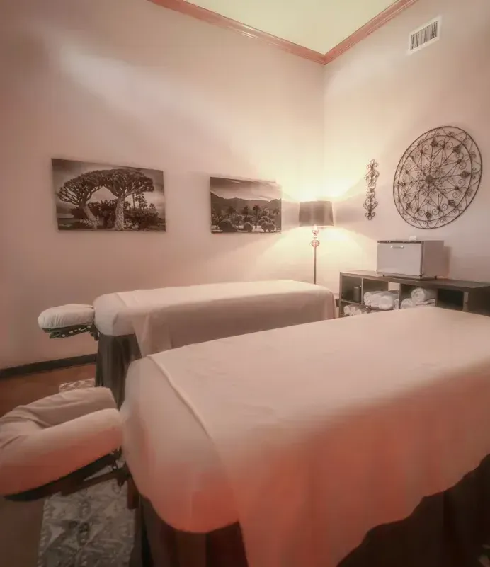 Two massage tables in a room with pictures on the wall